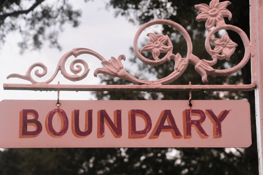 Boundaries - this image shows an ornate signpost in pink with the word boundary painted on it